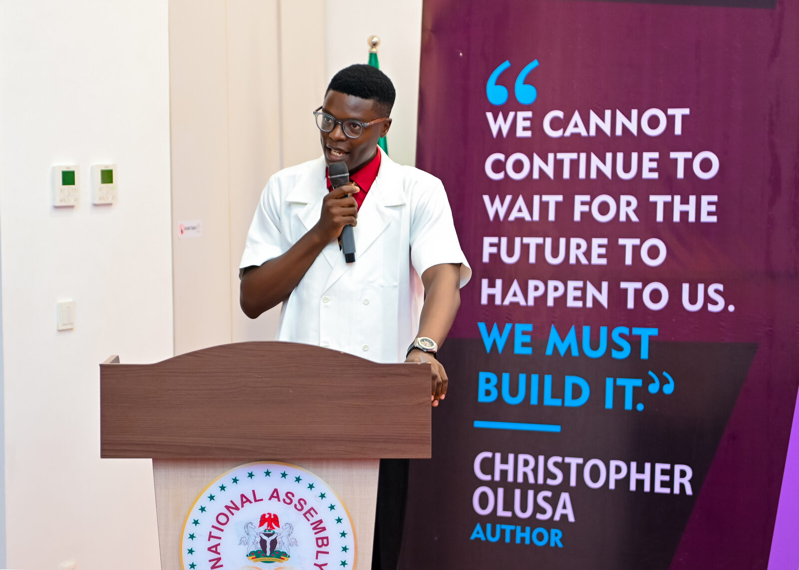 Christopher Olusa speaking at the podium at the National Assembly